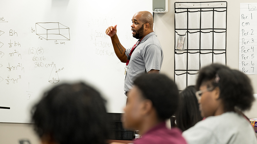Donald Yates III teaching geometry at a whiteboard to students in a classroom